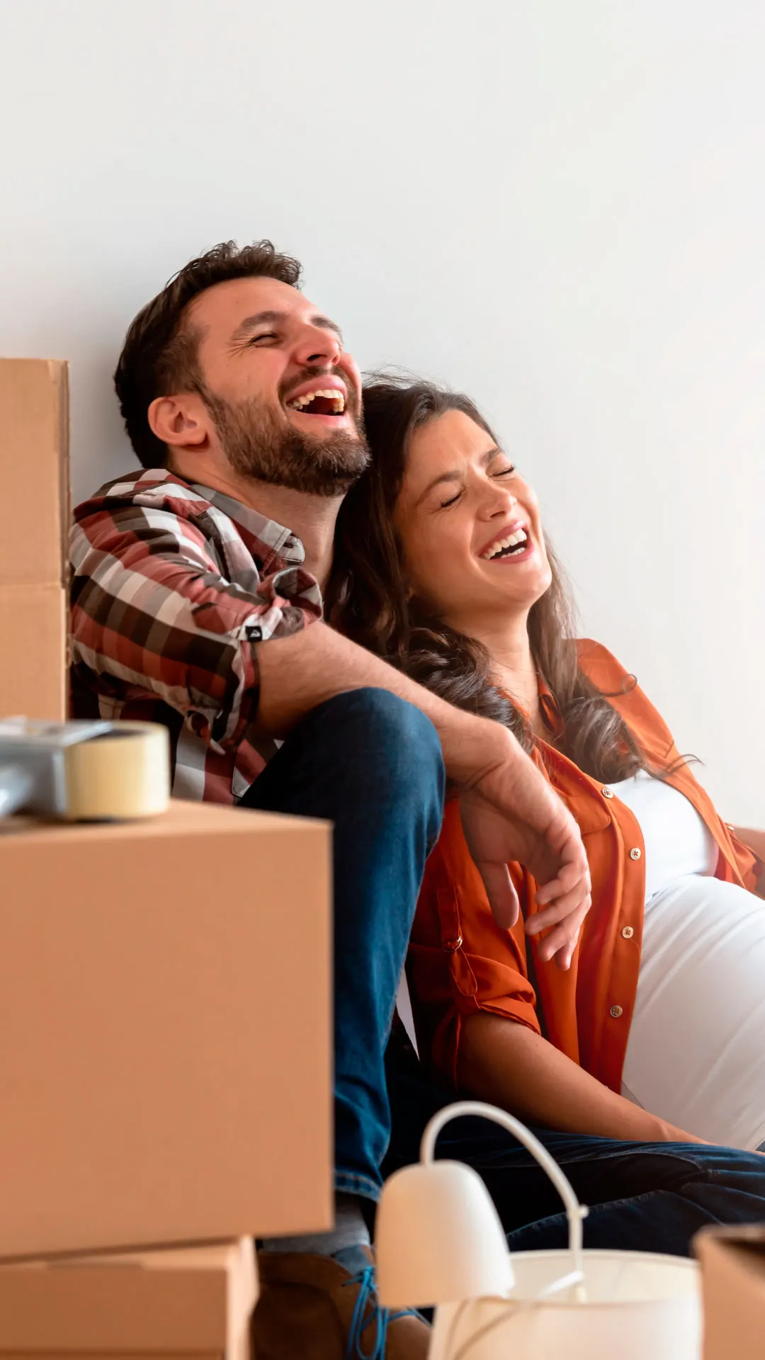 Pareja riendo entre cajas en su nueva casa