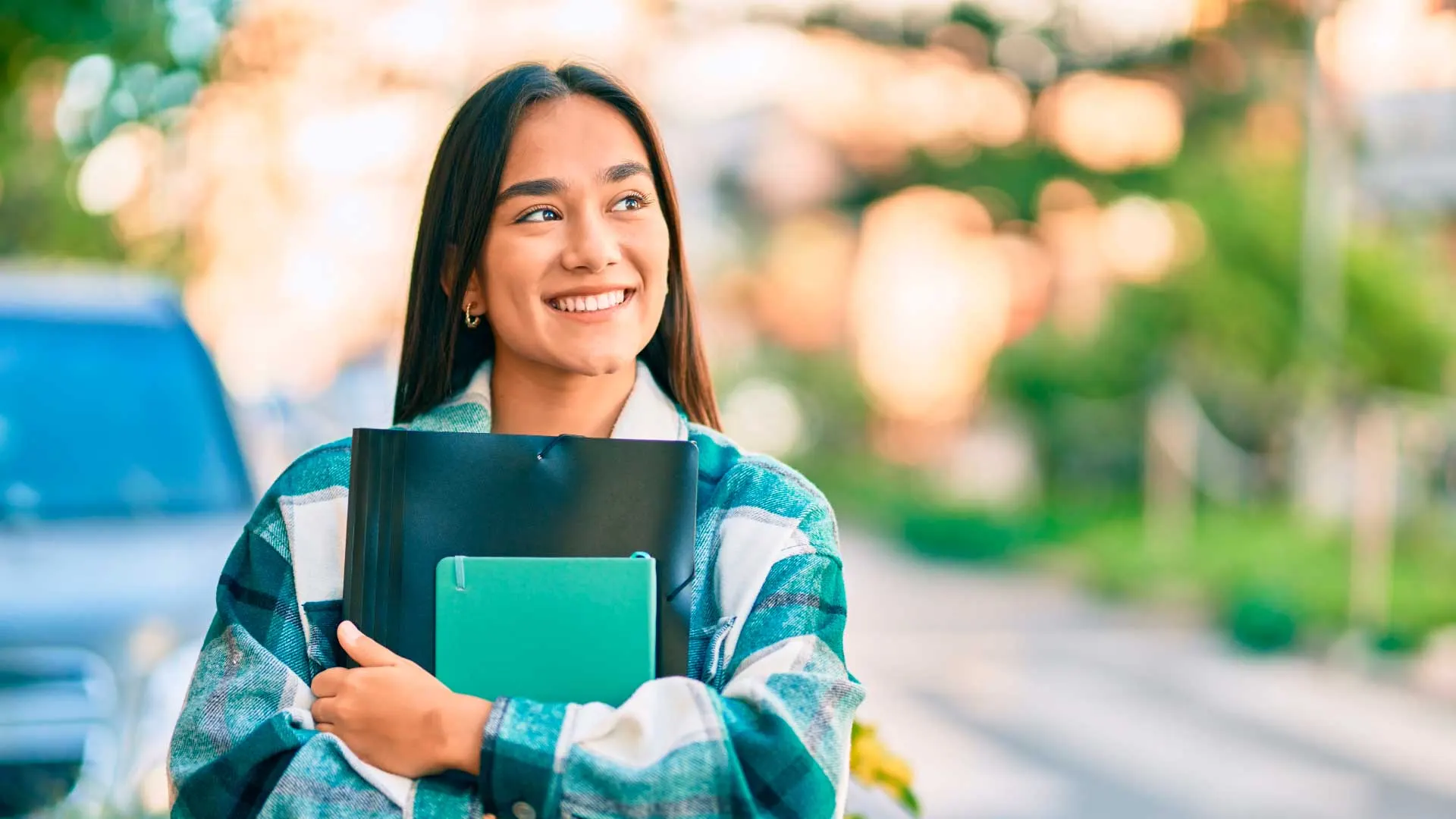 Estudiante sonriendo con sus carpetas, lista para mudarse